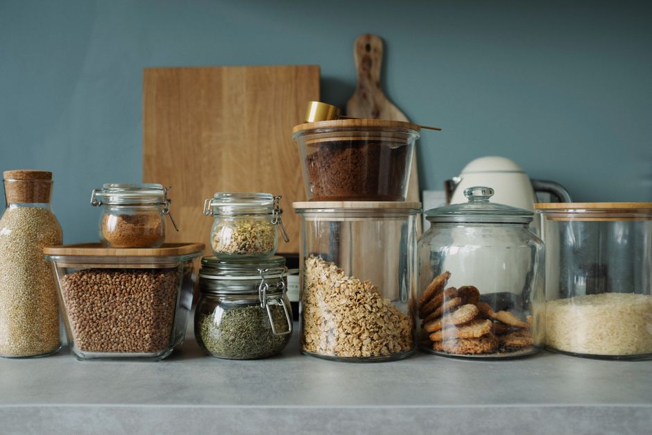Neatly arranged glass jars with cookies, oats, spices, and ingredients on a kitchen counter.