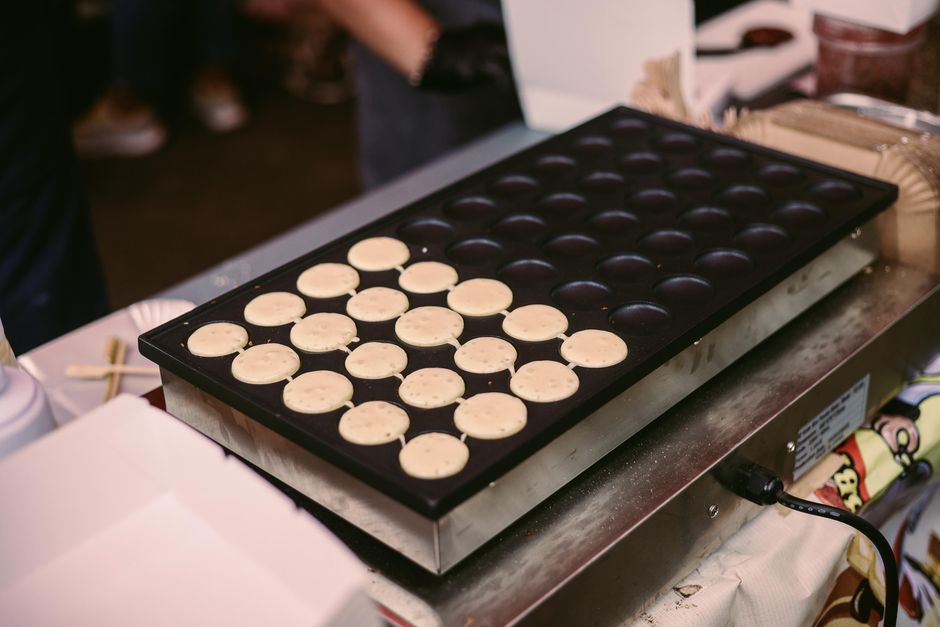 Fresh mini pancakes cooking on a griddle at a kitchen counter, ready to be served.